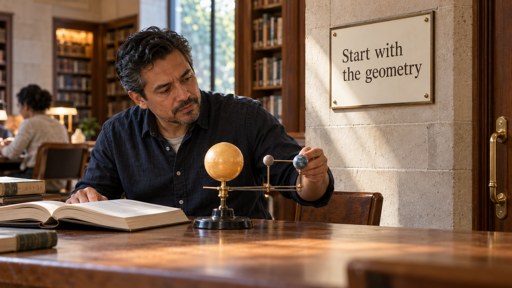 A reader examines an orbital teaching model beside an open reference book